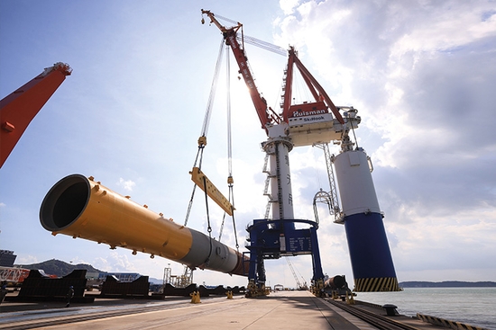Image of a Huisman heavy-lift crane loading a large industrial component at a port, illustrating Huisman’s B2B e-commerce success story with the Intershop platform.